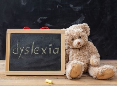Teddy Bear sitting beside chalkboard sign with Dyslexia written on it